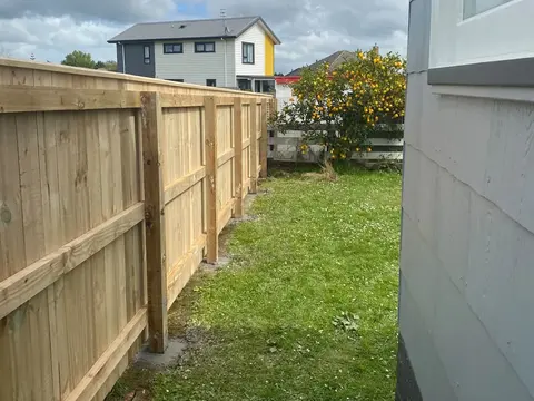 Capped timber fence with rails beside a house, Palmerston North