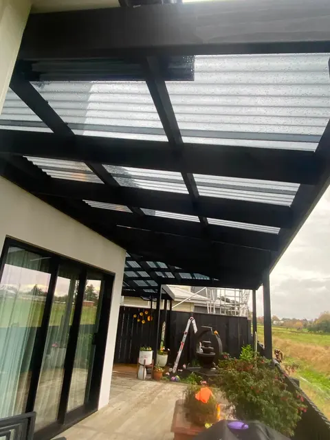Dark-framed deck roof with clear polycarbonate panels over a timber deck, Palmerston North