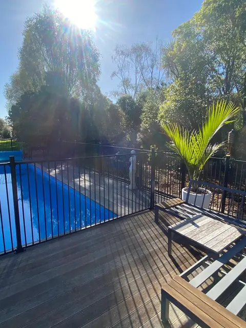 Timber pool deck beside a swimming pool and a pool fence, Palmerston North