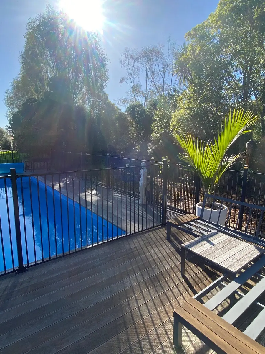 Timber pool deck beside a swimming pool and a pool fence, Palmerston North